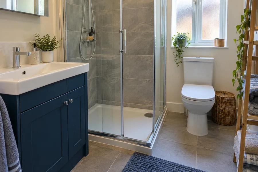 Navy vanity cupboard beside an enclosed shower and towel shelves