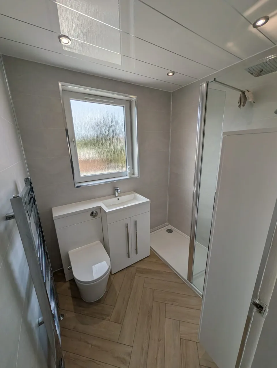 White vanity and toilet above a herringbone floor